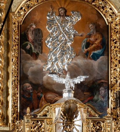 Zdjęcie nr 77: Drewniany, przyścienny ołtarz o formach architektonicznych, jednoosiowy, jednokondygnacyjny ze zwieńczeniem. Mensa murowana w kształcie prostopadłościanu zwieńczonego profilowanym gzymsem; antepedium prostokątne, w drewnianej, płaskorzeźbionej w motywy akantowe, złoconej ramie, dwustronne. Awers tłoczony, srebrzony, wykonany w technice papier mâché; rewers z malowanym na desce wyobrażeniem Veraicon na tle narzędzi męki. Tabernakulum na osi, złożone z mosiężnej, złoconej, sześciobocznej skrzynki w rozbudowanej, drewnianej obudowie o formach architektonicznych. Na nim tron wystawienia w kształcie niszy dekorowanej kratką, nakrytej kopułką z latarnią i przysłoniętej złapanymi po bokach kotarami. Na latarni rzeźbione przedstawienie pelikana karmiącego pisklęta własną krwią. Skrzynkę z tronem ulokowano na tle parawanu ustawionego na podwójnym cokole, ażurowego w górnej części, wypełnionego dekoracją roślinną, złączonego z kopułka spływami. 
Retabulum ołtarzowe drewniane wsparte na wysokim, dwudzielnym, murowanym cokole. Cokół w obudowie drewnianej, jego kondygnacje wydzielone wydatnymi, silnie występującymi przed lico gzymsami; mocno wysunięte ku przodowi części przednie. Ich lica z prostokątnymi płycinami mieszczącymi suchy akant; w części środkowej drugiej kondygnacji cokołu, dodatkowo pełnoplastyczne główki puttów. Na cokole ustawione zdwojone, złocone kolumny o skręconych trzonach i kompozytowych kapitelach. Pomiędzy nimi płyciny wypełnione dekoracją w formie podwieszonego wieńca, u jego szczytu putta pełniące rolę atlantów. Na tle płycin ustawione drewniane, złocone figury z lewej św. Zygmunta i z prawej św. Marii Magdaleny – patronów kościoła. Pole ołtarza z prostokątną niszą zamkniętą łukiem wyniesionym; ujętą płaskorzeźbioną, złoconą ramą zdobioną suchym akantem. W niszy pełnoplastyczny, polichromowany i złocony krucyfiks na aksamitnym tle, flankowany przez płaskorzeźbione wyobrażenia słońca i księżyca. Nisza zasuwana obrazem z Przemienieniem na górze Tabor, w drewnianej, złoconej sukience. Kolumny dźwigają pełne, wyłamane na osiach podpór belkowanie, z wydatnym, silnie profilowanym gzymsem; na jego osi złocony monogram „IHS” w otoku ze srebrzonych obłoków na tle promienistej glorii. Całość wieńczą fragmenty przerwanego przyczółka o formach wklęsło-wypukłych, z ażurową dekoracją z suchego akantu. Pomiędzy ramionami przyczółka złocona gloria promienista, w centrum której płaskorzeźbiona postać Boga Ojca siedzącego na srebrzonym obłoku ze srebrzoną gołębicą Ducha Świętego u stóp. Na ramionach glorii uskrzydlone główki puttów, niektóre na tle obłoków. Po bokach, na gzymsie siedzące postaci nagich, adorujących puttów. Ołtarz ujęty ażurowymi, złoconymi uszami z suchego akantu, w który wplecione są groteskowe putta trzymające pochodnie. Większość powierzchni ołtarza marmoryzowana, w kolorze jasnej, oliwkowej zieleni, z ciemniejszymi brązowymi elementami wypełniającymi płyciny. Złocenia w partiach ornamentów, kolumn oraz załamaniach profili elementów architektonicznych; srebrzone obłoki, części szat postaci i pelikan. 