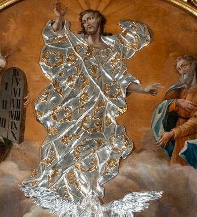 Zdjęcie nr 78: Drewniany, przyścienny ołtarz o formach architektonicznych, jednoosiowy, jednokondygnacyjny ze zwieńczeniem. Mensa murowana w kształcie prostopadłościanu zwieńczonego profilowanym gzymsem; antepedium prostokątne, w drewnianej, płaskorzeźbionej w motywy akantowe, złoconej ramie, dwustronne. Awers tłoczony, srebrzony, wykonany w technice papier mâché; rewers z malowanym na desce wyobrażeniem Veraicon na tle narzędzi męki. Tabernakulum na osi, złożone z mosiężnej, złoconej, sześciobocznej skrzynki w rozbudowanej, drewnianej obudowie o formach architektonicznych. Na nim tron wystawienia w kształcie niszy dekorowanej kratką, nakrytej kopułką z latarnią i przysłoniętej złapanymi po bokach kotarami. Na latarni rzeźbione przedstawienie pelikana karmiącego pisklęta własną krwią. Skrzynkę z tronem ulokowano na tle parawanu ustawionego na podwójnym cokole, ażurowego w górnej części, wypełnionego dekoracją roślinną, złączonego z kopułka spływami. 
Retabulum ołtarzowe drewniane wsparte na wysokim, dwudzielnym, murowanym cokole. Cokół w obudowie drewnianej, jego kondygnacje wydzielone wydatnymi, silnie występującymi przed lico gzymsami; mocno wysunięte ku przodowi części przednie. Ich lica z prostokątnymi płycinami mieszczącymi suchy akant; w części środkowej drugiej kondygnacji cokołu, dodatkowo pełnoplastyczne główki puttów. Na cokole ustawione zdwojone, złocone kolumny o skręconych trzonach i kompozytowych kapitelach. Pomiędzy nimi płyciny wypełnione dekoracją w formie podwieszonego wieńca, u jego szczytu putta pełniące rolę atlantów. Na tle płycin ustawione drewniane, złocone figury z lewej św. Zygmunta i z prawej św. Marii Magdaleny – patronów kościoła. Pole ołtarza z prostokątną niszą zamkniętą łukiem wyniesionym; ujętą płaskorzeźbioną, złoconą ramą zdobioną suchym akantem. W niszy pełnoplastyczny, polichromowany i złocony krucyfiks na aksamitnym tle, flankowany przez płaskorzeźbione wyobrażenia słońca i księżyca. Nisza zasuwana obrazem z Przemienieniem na górze Tabor, w drewnianej, złoconej sukience. Kolumny dźwigają pełne, wyłamane na osiach podpór belkowanie, z wydatnym, silnie profilowanym gzymsem; na jego osi złocony monogram „IHS” w otoku ze srebrzonych obłoków na tle promienistej glorii. Całość wieńczą fragmenty przerwanego przyczółka o formach wklęsło-wypukłych, z ażurową dekoracją z suchego akantu. Pomiędzy ramionami przyczółka złocona gloria promienista, w centrum której płaskorzeźbiona postać Boga Ojca siedzącego na srebrzonym obłoku ze srebrzoną gołębicą Ducha Świętego u stóp. Na ramionach glorii uskrzydlone główki puttów, niektóre na tle obłoków. Po bokach, na gzymsie siedzące postaci nagich, adorujących puttów. Ołtarz ujęty ażurowymi, złoconymi uszami z suchego akantu, w który wplecione są groteskowe putta trzymające pochodnie. Większość powierzchni ołtarza marmoryzowana, w kolorze jasnej, oliwkowej zieleni, z ciemniejszymi brązowymi elementami wypełniającymi płyciny. Złocenia w partiach ornamentów, kolumn oraz załamaniach profili elementów architektonicznych; srebrzone obłoki, części szat postaci i pelikan. 