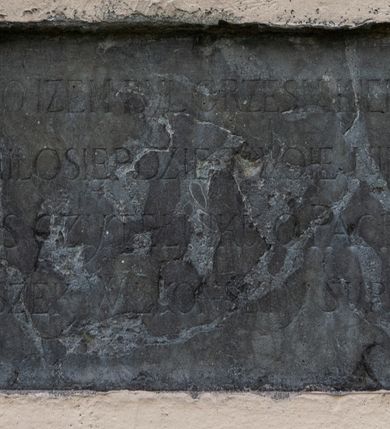 Zdjęcie nr 1: Tablica w kształcie leżącego prostokąta wmurowana w północną elewację kościoła. Umieszczono na niej, częściowo zakrytą inskrypcję o treści „WYZNAJĘ TO IŻEM BYŁ GRZESNIKIEM MÓJ BOŻ[E] / JEDNAKZE MIŁOSIE[R]DZIE TWOIE NIECH PRZEMOŻ[E] / CIEBIE ZAS CZYTELNIKU O PACIERZY PROS[ZĘ] / JA FRANCISZEK WILKONSKI Y SUPPLIKE WNOSZ[Ę]”. 