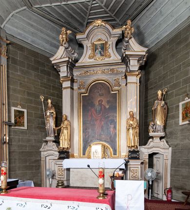 Zdjęcie nr 4: Ołtarz architektoniczny, jednoosiowy, jednokondygnacyjny, ze zwieńczeniem i bramkami bocznymi. Nastawa ujęta czworobocznymi kanelowanymi filarami umieszczonymi na tle kanelowanych pilastrów. Filary dźwigają pełne belkowanie i profilowany gzyms, występujące nad podporami, przerwane nad częścią środkową. Przy filarach rzeźby: po lewej Św. Piotr, po prawej Św. Paweł. W polu środkowym nastawy nisza w kształcie stojącego prostokąta zamkniętego łukiem półkolistym nadwieszonym, w profilowanej złoconej ramie. W niszy obraz z przedstawieniem św. Jakub Apostoła. Zwieńczenie w formie aedikuli zamkniętej łukiem półkolistym nadwieszonym, ujętej spływami wolutowymi. Pośrodku obraz w kształcie stojącego prostokąta, w ozdobnej ramie, z przedstawieniem św. Tekli w półpostaci. W osiach filarów odcinki przerwanego przyczółka, na których rzeźby siedzących puttów. Po bokach retabulum bramki z prześwitami w kształcie prostokąta zamkniętego łukiem kotarowym ściętym, w których osadzone płycinowe drzwi. Ponad bramkami konsole ujęte wolutami, na których rzeźby: po lewej Św. Wojciech, po prawej Św. Stanisław Biskup z Piotrowinem. W przyłuczach obrazu środkowego i we fryzie nałożone rzeźbione motywy rocaille’ów. Struktura nastawy w kolorze kremowym, ramy obrazów, kanelury, motywy ornamentalne złocone. 