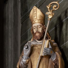 Zdjęcie nr 1: Rzeźba pełnoplastyczna, przyścienna; przedstawienie św. Stanisława Biskupa w całej postaci, frontalnie, w stroju pontyfikalnym. Prawą ręką błogosławi, lewą trzyma księgę i podtrzymuje pastorał. Po jego prawej stronie, u stóp, ukazany Piotrowin w półpostaci, ze złożonymi do modlitwy dłońmi. Karnacje w kolorze naturalnym, szaty pozłocone i srebrzyste.
