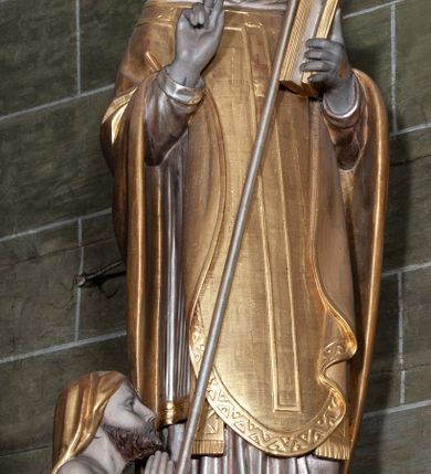 Zdjęcie nr 6: Rzeźba pełnoplastyczna, przyścienna; przedstawienie św. Stanisława Biskupa w całej postaci, frontalnie, w stroju pontyfikalnym. Prawą ręką błogosławi, lewą trzyma księgę i podtrzymuje pastorał. Po jego prawej stronie, u stóp, ukazany Piotrowin w półpostaci, ze złożonymi do modlitwy dłońmi. Karnacje w kolorze naturalnym, szaty pozłocone i srebrzyste.