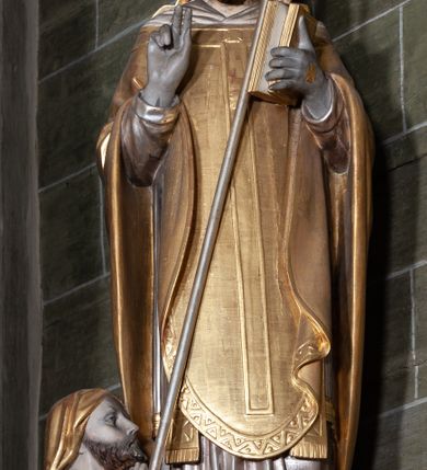 Zdjęcie nr 5: Rzeźba pełnoplastyczna, przyścienna; przedstawienie św. Stanisława Biskupa w całej postaci, frontalnie, w stroju pontyfikalnym. Prawą ręką błogosławi, lewą trzyma księgę i podtrzymuje pastorał. Po jego prawej stronie, u stóp, ukazany Piotrowin w półpostaci, ze złożonymi do modlitwy dłońmi. Karnacje w kolorze naturalnym, szaty pozłocone i srebrzyste.