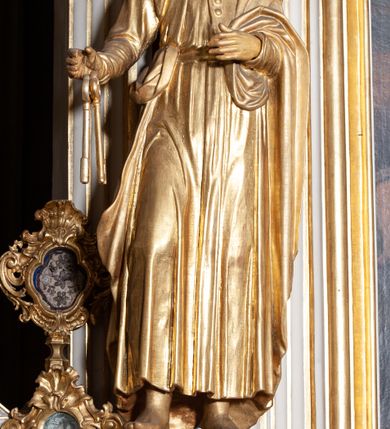 Zdjęcie nr 3: Rzeźba pełnoplastyczna, przyścienna; przedstawienie św. Piotra Apostoła w całej postaci, frontalnie, stoi boso w lekkim kontrapoście, z głową skierowaną lekko w lewo. Twarz starszego mężczyzny, pociągła, z wysokim czołem, okolona wianuszkiem sięgających ramion kręconych włosów i obfitym zarostem. Ręce ugięte w łokciach, w prawej trzyma dwa duże klucze. Ubrany w długą suknię z długimi, wąskimi rękawami, na lewe ramię zarzucony płaszcz przerzucony przez lewą rękę. Cała rzeźba wraz z karnacjami pozłocona.