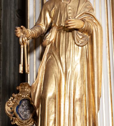 Zdjęcie nr 2: Rzeźba pełnoplastyczna, przyścienna; przedstawienie św. Piotra Apostoła w całej postaci, frontalnie, stoi boso w lekkim kontrapoście, z głową skierowaną lekko w lewo. Twarz starszego mężczyzny, pociągła, z wysokim czołem, okolona wianuszkiem sięgających ramion kręconych włosów i obfitym zarostem. Ręce ugięte w łokciach, w prawej trzyma dwa duże klucze. Ubrany w długą suknię z długimi, wąskimi rękawami, na lewe ramię zarzucony płaszcz przerzucony przez lewą rękę. Cała rzeźba wraz z karnacjami pozłocona.