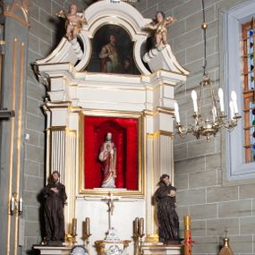 Zdjęcie nr 1: Ołtarz architektoniczny, jednoosiowy, jednokondygnacyjny, ze zwieńczeniem. Mensa drewniana, umieszczona na prostopadłościennej skrzyni; antependium z prostokątną płyciną. Nastawa ujęta czworobocznymi, kanelowanymi filarami, ustawionymi ukośnie na tle kanelowanych pilastrów. Filary dźwigają pełne belkowanie i profilowany gzyms, występujące nad nimi. Przy filarach od czoła na wysokich, prostopadłościennych postumentach rzeźby dwóch świętych jezuickich w czarnych sutannach. W polu środkowym nastawy prostokątne nisza ujęta złoconą ramą, w której rzeźba Najświętsze Serce Jezusa.  Zwieńczenie w kształcie aedikuli zamkniętej łukiem półkolistym nadwieszonym i o wklęsłych bokach; pośrodku obraz z przedstawieniem świętego męczennika powtarzający kształt aedikuli. Po bokach, w osiach filarów, odcinki przerwanego przyczółka, na których siedzą dwa putta. Struktura malowana na biało, detale architektoniczne i ornamenty złocone. 