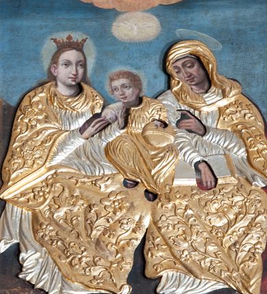 Zdjęcie nr 1: Obraz w kształcie stojącego prostokąta, w profilowanej, złoconej ramie. Przedstawienie Matki Boskiej i świętej Anny w całej postaci, siedzących na ławie, zwróconych lekko ku sobie. Pomiędzy nimi, pośrodku kompozycji siedzi kilkuletni Jezus. Za głowami postaci świetliste nimby. Na głowie Marii otwarta korona. Korpusy postaci osłonięte drewnianą złoconą i srebrzoną sukienką; płaszcze ozdobione motywami roślinnymi. W tle błękitne niebo. W górnej części, w osi pionowej nad Jezusem, wśród obłoków przedstawienie Boga Ojca w półpostaci, z rozłożonymi na boki rękoma oraz poniżej, w świetlistym owalu Gołębica Ducha Świętego.