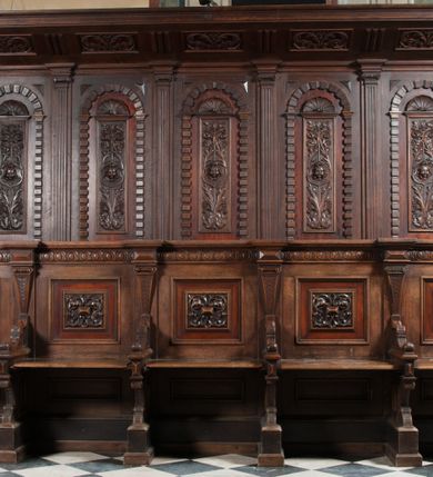 Zdjęcie nr 3: Stalle na rzucie wydłużonego prostokąta, dwurzędowe, pięcioosiowe. Zaplecek wysoki, zwieńczony baldachimem, od dołu poprzedzonym przez wąskie belkowanie, podtrzymywanym po bokach przez dwa wolutowe wsporniki osadzone na hermach. Pole zaplecka dzielone na pięć części, oddzielonych zdwojonymi pilastrami z głowicami zbliżonymi do jońskich; belkowanie przełamuje się na ich osi. W polach pomiędzy pilastrami pionowe prostokątne płyciny zwieńczone półkoliście, w profilowanych obramieniach, na zewnątrz których dodatkowo pasy boniowań. W polach płycin ornament roślinny z główką anielską w centrum, w zwieńczeniach płycin muszle. Siedziska od przodu poprzedzone ścianką z parapetem, która równocześnie pełni funkcję niskiego zaplecka dla drugiego rzędu siedzisk położonych niżej niż górne. Dolny zaplecek podzielony niskimi, hermowymi pilastrami, wspierającymi belkowanie, między pilastrami prostokątne płyciny w profilowanych obramieniach dekorowane rozetami z rautami pośrodku. Siedziska rozdzielone są niskimi podłokietnikami w formie wolut zdobionych cekinamii motywami roślinnymi. Na linii podłokietników, poniżej siedzisk widoczna ich kontynuacja w formie ścianek, u dołu masywna partia cokołowa.