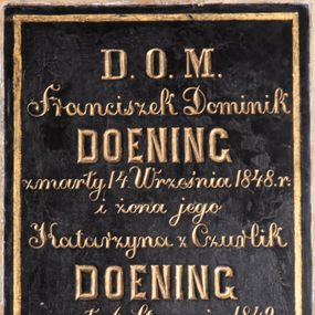 Zdjęcie nr 1: Tablica epitafijna w kształcie stojącego prostokąta, w polu wyznaczonym złotą, malowaną ramką inskrypcja:  „D(EO) O(PTIMO) M(AXIMO) / Franciszek Dominik / DOENING / zmarły 14. Września 1848. r(oku) / i żona jego / Katarzyna z Czurlik / DOENING / zmarła 6. Stycznia 1849. r(oku) / Ich dzieci i wnuki / proszą przechodniów / o Zdrowaś Marya!&quot;