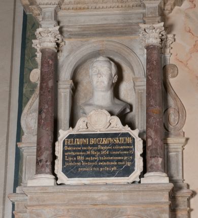 Zdjęcie nr 2: Epitafium przyścienne, architektoniczne, jednokondygnacyjne z uszami w formie spływów wolutowych. Podstawa w kształcie leżącego prostokąta z wyciętymi dwoma profilowanymi arkadami, w których umieszczono muszle palmetowe, podtrzymanymi przez spływy wolutowe. Powyżej wnęka w kształcie arkady flankowana kolumienkami z korynckimi kapitelami, podtrzymującymi przełamane belkowanie. Wewnątrz wnęki popiersie zmarłego. Zmarły ujęty do ramion, zwrócony na wprost, z szeroko otwartymi oczami, krótkim, szerokim nosem oraz szerokimi ustami o kącikach skierowanych w dół. Włosy krótkie, z przedziałkiem, zaczesane na boki. Poniżej na tablicy inskrypcja „FELIXOWI BOCZKOWSKIEMU / Doktorowi medycyny Fizykowi salinarnemu / urodzonemu 30 Maja 1804 roku zmarłemu 23 / Lipca 1855 mężowi szlachetnemu przy/jacielowi biednych świadkowie cnót jego / pomnik ten położyli”. Tablica ujęta obramieniem z motywem rollwerku, zwieńczona kartuszem z godłem herbu Gozdawa. Zwieńczenie epitafium w formie trójkątnego przyczółka z motywem wolich oczu i ząbkowaniem wewnątrz; na szczycie i w narożach zdobione akroterionami.