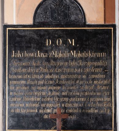 Zdjęcie nr 1: Tablica epitafijna w kształcie zbliżonym do kwadratu, na osi zwieńczona pełnym łukiem, w którego polu umieszczono herb. W polu tarczy znajduje się godło herbu Gryf, zaś nad tarczą otwarta korona z klejnotem – półgryf z trąbą. Na tablicy inskrypcja  „D(EO) O(PTIMO) M(AXIMO) / Jakubowi Jaxa z Mąkolic Mąkolskiemu / Prezesowi Sądu Appellacyjnego byłej Rzeczypospolitej / Krakowskiej w Wieliczce d(nia) 18 Czerwca. 1858 r(oku) zgasłemu, - / liczącemu lat 82. który od młodości poświęciwszy się zawodowi / prawnemu, Urzędy pod trzema Rządami, lat 50. przeszło nieskazytel/nie piastując, na miano prawego Urzędnika zasłużył. Mężowi / w nauce praw biegłemu, w stanie małżeńskim przykładnemu Ojcu / czułemu, Obywatelowi o dobro Ojczyzny gorliwemu i przyjacielowi / wiernemu, w dowód niewygasłej wdzięczności Exekutor Testa/mentu, ten pomnik wystawił, prosząc czytelnika o modlitwę za Jego / duszę do Boga”.