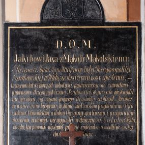 Zdjęcie nr 1: Tablica epitafijna w kształcie zbliżonym do kwadratu, na osi zwieńczona pełnym łukiem, w którego polu umieszczono herb. W polu tarczy znajduje się godło herbu Gryf, zaś nad tarczą otwarta korona z klejnotem – półgryf z trąbą. Na tablicy inskrypcja  „D(EO) O(PTIMO) M(AXIMO) / Jakubowi Jaxa z Mąkolic Mąkolskiemu / Prezesowi Sądu Appellacyjnego byłej Rzeczypospolitej / Krakowskiej w Wieliczce d(nia) 18 Czerwca. 1858 r(oku) zgasłemu, - / liczącemu lat 82. który od młodości poświęciwszy się zawodowi / prawnemu, Urzędy pod trzema Rządami, lat 50. przeszło nieskazytel/nie piastując, na miano prawego Urzędnika zasłużył. Mężowi / w nauce praw biegłemu, w stanie małżeńskim przykładnemu Ojcu / czułemu, Obywatelowi o dobro Ojczyzny gorliwemu i przyjacielowi / wiernemu, w dowód niewygasłej wdzięczności Exekutor Testa/mentu, ten pomnik wystawił, prosząc czytelnika o modlitwę za Jego / duszę do Boga”.