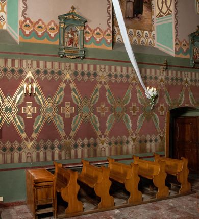 Zdjęcie nr 4: Prezbiterium: 
Sklepienie kolebkowe z lunetami; trójprzęsłowe. Pola malowane  są na kolor biały z centralnie umieszczonymi kolistymi medalionami. W przęśle pierwszym od ołtarza znajduje się motyw krzyża greckiego na tle promienistej glorii; w drugim gołębica Ducha Świętego na tle analogicznej glorii zamknięta w polu przypominającym sześciolistny kwiat o błękitno-złotych płatkach; w trzecim znak Trójcy Świętej w formie trzech przecinających się okręgów z napisem „TRI/NI/TAS”, otoczonych promieniami i płomienistymi półokręgami. Pozostałe partie pól sklepienia wypełnione są złoconymi językami ognia. Wokół pól sklepienia biegnie ornament geometryczny w kolorze turkusowym z elementami ugru i ultramaryny. Lunety malowane są na kolor jasnoniebieski. W każdej z nich znajdują się medaliony o kształcie zbliżonym do czwórliścia, wewnątrz których, od wschodu jest: słońce, planeta, gwiazda, księżyc, monogram Chrystusa, napis „CA/RI/TAS”.  Ściany boczne w około połowie wysokości podzielone na dwa poziomy. Dolny wypełniony jest geometryczną dekoracją w formie fryzu ze złoconych rombów, naprzemiennie większych i mniejszych. Wewnątrz figur równoramienne krzyże oraz motyw uproszczonych liści. Fryz ujęty od góry i dołu abstrakcyjną dekoracją o charakterze geometrycznym. Tła malowane są na kolor ciemnoczerwony oraz zielony. Poziom górny malowany jest na bladoróżowo. Na wysokości parapetów okiennych fryz ze stylizowanych motywów kwiatowych w kolorze żółtym, zielonym i brązowym. W ościeżach dekoracja ramowa w kolorze turkusowym i bladożółtym wzbogacona o malowane ciemniejszą farbą motywy geometryczne. Okna ściany południowej zastąpione blendami; w nich motyw karpiej łuski wypełnionej palmetą.

Łuk arkady tęczowej:
Na licu arkady tęczowej znajduje się figuralne przedstawienie stygmatyzacji św. Franciszka. Z lewej strony św. Franciszek, zwrócony w lewą stronę, z rozłożonymi szeroko rękami i prawą nogą cofniętą do tyłu. Ubrany w brązowy habit franciszkański. Z prawej strony Chrystus, ukazany naturalnej wielkości, jako cherubin o dużych, czerwonych skrzydłach. Z jego ran wychodzą promienie tworzące stygmaty na ciele świętego. Scena rozgrywa się na kamienistej drodze, na tle płomieni. Kompozycja ujęta otokiem z białych chmur. Na podłuczu arkady symetryczna dekoracja geometryczna w formie motywu „jodełki” przedzielonego wstęgą. W osi ośmioboczne pole ze znakiem krzyża greckiego z napisem „Cristus/Jesus”. Kolorystyka utrzymana w ciemnej zieleni, ceglastej czerwieni oraz w kolorze złotym.

Nawa główna:
Sklepienie kolebkowe z lunetami, czteroprzęsłowe. Pola malowane kolorem jasnoniebieskim. Cała długość nawy połączona dekoracyjnym pasem w kolorach turkusowym, szafirowym oraz żółtym. W każdym z przęseł pośrodku czteorolistne  pole otoczone glorią promienistą zawierające znaki, od wschodu: Alfa i Omega, monogram maryjny, kielich z hostią, IHS. Lunety malowane na jasnożółto, pośrodku każdej owoidalne pole w kolorze szafirowym: od wschodu i zachodu po dwóch stronach korona i napis „VITA / AETERNA”, od południa waga i napis „IUSTI/TIA”, dalej miecz i napis „FORTI\TUDO”, od północy beczka i napis „TEM/PE/RANTIA, wąż i napis „PRUDENTIA”. Obramienia lunet z motywem abstrakcyjnym. Pasy gurtów z ludowymi motywami kwiatowymi i kłosami zboża na żółtym tle. Ściany boczne w partii cokołu malowane są na kolor różowy, powyżej aż do linii parapetów okiennych: miodowo-żółty. Na obramieniach arkadowych nisz jest stylizowana dekoracja roślinna, w podłuczach i ościeżach arkad dekoracja analogiczna do tej z podłucza arkady tęczy. Na ścianach pomiędzy niszami godła franciszkańskie zamknięte w okrągłych medalionach. Na linii parapetów geometryczny fryz z przecinających się arkadek uzupełnionych o motywy roślinne. W rozglifieniach okiennych naprzemiennie motywy geometryczne i roślinne w kolorach błękitnym, pomarańczoym i dwóch odcieniach żółci. Arkada chóru muzycznego o podziale ramowym w kolorach jasnozielonym, pomarańczowym i żółtym.