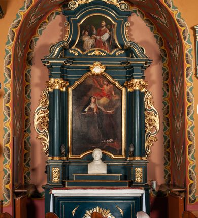 Zdjęcie nr 1: Ołtarz przyścienny, architektoniczny, jednokondygnacyjny, jednoosiowy, ze zwieńczeniem.  Mensa w formie prostopadłościanu. Antepedium proste z płaskorzeźbionym przedstawieniem Baranka Bożego w polu. Retabulum umieszczone na zdwojonym cokole, flankowane kolumnami, ustawionymi na tle zwielokrotnionych pilastrów podtrzymujących wyłamane belkowanie; na osi kolumn przerwany wolutowy przyczółek. W polu głównym nastawy płytka wnęka, ujęte złoconą i profilowaną ramą w kształcie stojącego prostokąta zamkniętego łukiem wklęsło-wypukłym z uskokami. Pośrodku obraz „Św. Kinga”. W górnej części ramy złocony kartusz. Zwieńczenie o delikatnie wklęsłych bokach ujętych spływami wolutowymi, zamknięte łukiem nadwieszonym. Nad nim złocona muszla palmetowa między dwoma spływami wolutowymi. W polu zwieńczenia obraz „Św. Walenty” w ramie o fantazyjnym wykroju. Retabulum flankowane po bokach ażurowymi uszami utworzonymi z liści akantu i przeplatającej je karbowanej wstęgi. Podpory ustawione na bazach, kapitele kompozytowe, trzony kolumn gładkie, natomiast trzony pilastrów kanelowane. Struktura malowana w kolorze ciemnozielonym, ornamenty i detale złocone.

