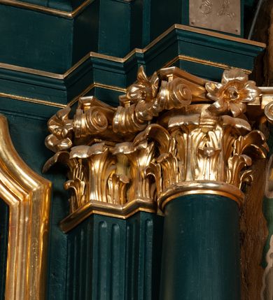 Zdjęcie nr 11: Ołtarz przyścienny, architektoniczny, jednokondygnacyjny, jednoosiowy, ze zwieńczeniem.  Mensa w formie prostopadłościanu. Antepedium malowane: pośrodku medalion otoczony wieńcem z kwiatów. W polu otwarta księga z napisem „SIQUAE/RIS / MIRA/CULA” oraz skrzyżowane dwie gałązki palmowe, kajdany i kule inwalidzkie. Po bokach medalionu wolutowo zakręcona wić roślinna zakończona wazonami z kwiatami. Całość ukazana na ciemnozielonym tle. Tabernakulum w formie prostopadłościennej skrzynki, ustawione na niskim cokole, flankowane parą pilastrów z bazami, kanelowanymi trzonami i kapitelami kompozytowymi podtrzymującymi proste belkowanie z trójkątnym przyczółkiem. Zwieńczenie w formie prostopadłościennego postumentu, na którym ustawiony jest krucyfiks. Drzwiczki w kształcie stojącego prostokąta, zamkniętego łukiem nadwieszonym. W polu monogram IHS, poniżej narzędzia Męki Pańskiej. Nad drzwiczkami, w przyłuczach dwie gałązki róż. Retabulum umieszczone na zdwojonym cokole, flankowane kolumnami, ustawionymi na tle zwielokrotnionych pilastrów podtrzymujących wyłamane belkowanie; na osi kolumn przerwany wolutowy przyczółek. W polu głównym nastawy płytka wnęka, ujęta złoconą i profilowaną ramą w kształcie stojącego prostokąta zamkniętego łukiem wklęsło-wypukłym z uskokami. Pośrodku obraz „Św. Antoni Padewski”, a nad nim kartusz z napisem „S(WIĘTY) ANTONI MÓDL SIĘ ZA NAMI”. W górnej części ramy drugi, mniejszy kartusz z napisem „IHS”. Zwieńczenie o delikatnie wklęsłych bokach ujętych spływami wolutowymi i rzędem kampanul, zamknięte łukiem nadwieszonym. Nad nim złocona muszla palmetowa ujęta dwoma spływami wolutowymi. U szczytu zwieńczenia, po bokach ustawione dwa wazoniki z kwiatami. W polu zwieńczenia obraz „Św. Jan Nepomucen” ujęty w ramę o fantazyjnym wykroju. Podpory ustawione na bazach, kapitele kompozytowe, trzony kolumn gładkie, natomiast trzony pilastrów kanelowane. Struktura malowana w kolorze ciemnozielonym, ornamenty i detale złocone.