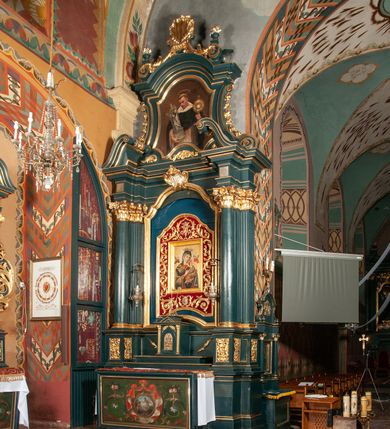 Zdjęcie nr 1: Ołtarz przyścienny, architektoniczny, jednokondygnacyjny, jednoosiowy, ze zwieńczeniem.  Mensa w formie prostopadłościanu. Antepedium malowane: pośrodku medalion otoczony baldachimem utworzonym z królewskiego płaszcza, spiętego u góry koroną, z chwostami po bokach. W polu scena ukazująca odnalezienie pierścienia św. Kingi w bryle soli. Po bokach medalionu wolutowo zakręcona wić roślinna zakończona wazonami z kwiatami. Całość ukazana na ciemnozielonym tle. Tabernakulum w formie prostopadłościennej skrzynki, ustawione na niskim cokoliku, flankowane parą pilastrów z bazami, kanelowanymi trzonami i kapitelami kompozytowymi podtrzymującymi proste belkowanie z trójkątnym przyczółkiem. Zwieńczenie w formie prostopadłościennego postumentu, na którym ustawiony krucyfiks. Drzwiczki w kształcie stojącego prostokąta, zamkniętego łukiem nadwieszonym. W polu monogram Marii, gwiazda i wieniec z róż. Nad drzwiczkami, w przyłuczach dwie gałązki róż. Retabulum umieszczone na zdwojonym cokole, flankowane kolumnami, ustawionymi na tle zwielokrotnionych pilastrów podtrzymujących wyłamane belkowanie; na osi kolumn przerwany wolutowy przyczółek. W polu głównym nastawy płytka wnęka, ujęta złoconą i profilowaną ramą w kształcie stojącego prostokąta zamkniętego łukiem wklęsło-wypukłym z uskokami. Pośrodku obraz „Matki Boskiej Nieustającej Pomocy”, a na zasuwie obraz „Matki Boskiej Niepokalanie Poczętej”. W górnej części ramy złocony kartusz z napisem „MARIA”. Zwieńczenie o delikatnie wklęsłych bokach ujętych spływami wolutowymi i rzędem kampanul, zamknięte łukiem nadwieszonym z profilowanym gzymsem. Nad nim złocona muszla palmetowa ujęta dwoma spływami wolutowymi. U szczytu zwieńczenia, po bokach ustawione dwa wazoniki z kwiatami. W polu zwieńczenia obraz „Św. Jacek” ujęty w ramę o fantazyjnym wykroju.  Podpory ustawione na bazach, kapietle kompozytowe, trzony kolumn gładkie, natomiast trzony pilastrów kanelowane. Struktura malowana w kolorze ciemnozielonym, ornamenty i detale złocone.
