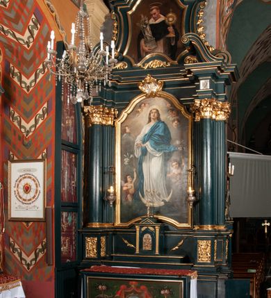 Zdjęcie nr 8: Ołtarz przyścienny, architektoniczny, jednokondygnacyjny, jednoosiowy, ze zwieńczeniem.  Mensa w formie prostopadłościanu. Antepedium malowane: pośrodku medalion otoczony baldachimem utworzonym z królewskiego płaszcza, spiętego u góry koroną, z chwostami po bokach. W polu scena ukazująca odnalezienie pierścienia św. Kingi w bryle soli. Po bokach medalionu wolutowo zakręcona wić roślinna zakończona wazonami z kwiatami. Całość ukazana na ciemnozielonym tle. Tabernakulum w formie prostopadłościennej skrzynki, ustawione na niskim cokoliku, flankowane parą pilastrów z bazami, kanelowanymi trzonami i kapitelami kompozytowymi podtrzymującymi proste belkowanie z trójkątnym przyczółkiem. Zwieńczenie w formie prostopadłościennego postumentu, na którym ustawiony krucyfiks. Drzwiczki w kształcie stojącego prostokąta, zamkniętego łukiem nadwieszonym. W polu monogram Marii, gwiazda i wieniec z róż. Nad drzwiczkami, w przyłuczach dwie gałązki róż. Retabulum umieszczone na zdwojonym cokole, flankowane kolumnami, ustawionymi na tle zwielokrotnionych pilastrów podtrzymujących wyłamane belkowanie; na osi kolumn przerwany wolutowy przyczółek. W polu głównym nastawy płytka wnęka, ujęta złoconą i profilowaną ramą w kształcie stojącego prostokąta zamkniętego łukiem wklęsło-wypukłym z uskokami. Pośrodku obraz „Matki Boskiej Nieustającej Pomocy”, a na zasuwie obraz „Matki Boskiej Niepokalanie Poczętej”. W górnej części ramy złocony kartusz z napisem „MARIA”. Zwieńczenie o delikatnie wklęsłych bokach ujętych spływami wolutowymi i rzędem kampanul, zamknięte łukiem nadwieszonym z profilowanym gzymsem. Nad nim złocona muszla palmetowa ujęta dwoma spływami wolutowymi. U szczytu zwieńczenia, po bokach ustawione dwa wazoniki z kwiatami. W polu zwieńczenia obraz „Św. Jacek” ujęty w ramę o fantazyjnym wykroju.  Podpory ustawione na bazach, kapietle kompozytowe, trzony kolumn gładkie, natomiast trzony pilastrów kanelowane. Struktura malowana w kolorze ciemnozielonym, ornamenty i detale złocone.

