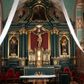 Zdjęcie nr 1: Ołtarz drewniany, dwustronny, obecnie przyścienny, architektoniczny, jednokondygnacyjny ze zwieńczeniem, trójosiowy, z bramkami. Mensa kamienna, prostopadłościenna z antepedium ujętym w profilowaną i złoconą ramę, dekorowaną kimationem jońskim i kampanulami. W polu płaskorzeźbione przedstawienie kielicha z hostią ujętego dwoma otwartymi księgami z napisem na prawej „ECCE / PANIS / ANGE/LORUM”, na lewej „EVAN/GE/LIUM”; liśćmi laurowymi, arma Christi; u podstawy kielicha nałożona korona cierniowa. W dolnych narożach antepedium dekoracja z miękko zawijającej się wstęgi regencyjnej. Tabernakulum o rozbudowanych architektonicznych formach, jednokondygnacyjne, trójosiowe, każda z osi flankowana parą kolumienek i zakończona zwieńczeniem. W osi środkowej tabernakulum metalowe: w dolnej części w formie prostopadłościennej skrzynki z wizerunkiem Chrystusa, w górnej części obrotowe z przedstawieniem Baranka Bożego, zamknięte ozdobnym zwieńczeniem z parą uskrzydlonych putt i koroną w typie zamkniętym. W polach osi bocznych umieszczone za szybką relikwie świętych ujęte prostokątną, złoconą ramą. Retabulum ustawione na wysokim, dwudzielnym cokole, z bramkami o otworach drzwiowych zamkniętych łukiem kotarowym ściętym, nadproża w formie profilowanego gryzmsu. Pole ołtarza, zarówno osi głównej jak i bocznych ujęte jest kolumnami o gładkich trzonach i złoconych kapitalach kompozytowych ustawionych na tle zwieloktrotnionych pilastrów o kanelowanych trzonach. Podpory dźwigają wyłamane na ich osi, pełne belkowanie z wydatnym, silnie profilowanych gzymsem. Na nim fragmenty przyczółka w formie wolut. Pole osi środkowej ze złoconą ramą zamkniętą łukiem wklęsło-wypukłym z uskokiem. W zwieńczeniu ramy wolutowy kartusz o nieregularnym kształcie, z napisem „CONSUMMATUM / EST”. W centrum pola ołtarzowego drewniany krycyfiks. W osi prawej figura św. Kazimierza Królewicza, w osi lewej figura św. Jadwigi Śląskiej. Rzeźby ustawione w niszach, zamkniętych łukiem wklęsło-wypukłym, na rozbudowanych, wolutowych konsolach dekorowanych z przodu kartuszem utworzonym z akantowego wieńca wypełnionego kratką regencyjną; ponad nim girlanda złożona z kampanul i kwiatów. W niszach ponad figurami umieszczone dużych rozmiarów, złocone muszle palmetowe, oraz nieco niżej dwie gałązki akantu. Ponad niszami rozbudowana płaskorzeźbiona dekoracja w formie struktury utworzonej z wolut o karbowanych wypełnieniach, w jej centrum uskrzydlone główki aniołków. Zwieńczenie w formie wklęsło-wypukłej, zamknięte gzymsem w kształcie łuku nadwieszonego, po bokach flankowane dwoma wazonami z kwiatami. W polu obraz św. Michała Archanioła. Kolorystyka ciemnozielona, ze złoceniami w partiach ornamentów oraz w załamaniach profili architektonicznych. Partie cokołu dekorowane płycinami wypełnionymi ornamentem regencyjnym. Według dokumentacji konserwatorskiej na odwrociu ołtarza znajduje się malowana iluzjonistyczna dekoracja przedstawiająca barokowy ołtarz, postacie Matki Boskiej, św. Jana Ewangelisty oraz świętych franciszkańskich.

