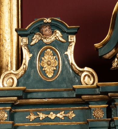 Zdjęcie nr 27: Ołtarz drewniany, dwustronny, obecnie przyścienny, architektoniczny, jednokondygnacyjny ze zwieńczeniem, trójosiowy, z bramkami. Mensa kamienna, prostopadłościenna z antepedium ujętym w profilowaną i złoconą ramę, dekorowaną kimationem jońskim i kampanulami. W polu płaskorzeźbione przedstawienie kielicha z hostią ujętego dwoma otwartymi księgami z napisem na prawej „ECCE / PANIS / ANGE/LORUM”, na lewej „EVAN/GE/LIUM”; liśćmi laurowymi, arma Christi; u podstawy kielicha nałożona korona cierniowa. W dolnych narożach antepedium dekoracja z miękko zawijającej się wstęgi regencyjnej. Tabernakulum o rozbudowanych architektonicznych formach, jednokondygnacyjne, trójosiowe, każda z osi flankowana parą kolumienek i zakończona zwieńczeniem. W osi środkowej tabernakulum metalowe: w dolnej części w formie prostopadłościennej skrzynki z wizerunkiem Chrystusa, w górnej części obrotowe z przedstawieniem Baranka Bożego, zamknięte ozdobnym zwieńczeniem z parą uskrzydlonych putt i koroną w typie zamkniętym. W polach osi bocznych umieszczone za szybką relikwie świętych ujęte prostokątną, złoconą ramą. Retabulum ustawione na wysokim, dwudzielnym cokole, z bramkami o otworach drzwiowych zamkniętych łukiem kotarowym ściętym, nadproża w formie profilowanego gryzmsu. Pole ołtarza, zarówno osi głównej jak i bocznych ujęte jest kolumnami o gładkich trzonach i złoconych kapitalach kompozytowych ustawionych na tle zwieloktrotnionych pilastrów o kanelowanych trzonach. Podpory dźwigają wyłamane na ich osi, pełne belkowanie z wydatnym, silnie profilowanych gzymsem. Na nim fragmenty przyczółka w formie wolut. Pole osi środkowej ze złoconą ramą zamkniętą łukiem wklęsło-wypukłym z uskokiem. W zwieńczeniu ramy wolutowy kartusz o nieregularnym kształcie, z napisem „CONSUMMATUM / EST”. W centrum pola ołtarzowego drewniany krycyfiks. W osi prawej figura św. Kazimierza Królewicza, w osi lewej figura św. Jadwigi Śląskiej. Rzeźby ustawione w niszach, zamkniętych łukiem wklęsło-wypukłym, na rozbudowanych, wolutowych konsolach dekorowanych z przodu kartuszem utworzonym z akantowego wieńca wypełnionego kratką regencyjną; ponad nim girlanda złożona z kampanul i kwiatów. W niszach ponad figurami umieszczone dużych rozmiarów, złocone muszle palmetowe, oraz nieco niżej dwie gałązki akantu. Ponad niszami rozbudowana płaskorzeźbiona dekoracja w formie struktury utworzonej z wolut o karbowanych wypełnieniach, w jej centrum uskrzydlone główki aniołków. Zwieńczenie w formie wklęsło-wypukłej, zamknięte gzymsem w kształcie łuku nadwieszonego, po bokach flankowane dwoma wazonami z kwiatami. W polu obraz św. Michała Archanioła. Kolorystyka ciemnozielona, ze złoceniami w partiach ornamentów oraz w załamaniach profili architektonicznych. Partie cokołu dekorowane płycinami wypełnionymi ornamentem regencyjnym. Według dokumentacji konserwatorskiej na odwrociu ołtarza znajduje się malowana iluzjonistyczna dekoracja przedstawiająca barokowy ołtarz, postacie Matki Boskiej, św. Jana Ewangelisty oraz świętych franciszkańskich.

