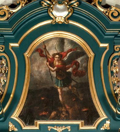 Zdjęcie nr 35: Ołtarz drewniany, dwustronny, obecnie przyścienny, architektoniczny, jednokondygnacyjny ze zwieńczeniem, trójosiowy, z bramkami. Mensa kamienna, prostopadłościenna z antepedium ujętym w profilowaną i złoconą ramę, dekorowaną kimationem jońskim i kampanulami. W polu płaskorzeźbione przedstawienie kielicha z hostią ujętego dwoma otwartymi księgami z napisem na prawej „ECCE / PANIS / ANGE/LORUM”, na lewej „EVAN/GE/LIUM”; liśćmi laurowymi, arma Christi; u podstawy kielicha nałożona korona cierniowa. W dolnych narożach antepedium dekoracja z miękko zawijającej się wstęgi regencyjnej. Tabernakulum o rozbudowanych architektonicznych formach, jednokondygnacyjne, trójosiowe, każda z osi flankowana parą kolumienek i zakończona zwieńczeniem. W osi środkowej tabernakulum metalowe: w dolnej części w formie prostopadłościennej skrzynki z wizerunkiem Chrystusa, w górnej części obrotowe z przedstawieniem Baranka Bożego, zamknięte ozdobnym zwieńczeniem z parą uskrzydlonych putt i koroną w typie zamkniętym. W polach osi bocznych umieszczone za szybką relikwie świętych ujęte prostokątną, złoconą ramą. Retabulum ustawione na wysokim, dwudzielnym cokole, z bramkami o otworach drzwiowych zamkniętych łukiem kotarowym ściętym, nadproża w formie profilowanego gryzmsu. Pole ołtarza, zarówno osi głównej jak i bocznych ujęte jest kolumnami o gładkich trzonach i złoconych kapitalach kompozytowych ustawionych na tle zwieloktrotnionych pilastrów o kanelowanych trzonach. Podpory dźwigają wyłamane na ich osi, pełne belkowanie z wydatnym, silnie profilowanych gzymsem. Na nim fragmenty przyczółka w formie wolut. Pole osi środkowej ze złoconą ramą zamkniętą łukiem wklęsło-wypukłym z uskokiem. W zwieńczeniu ramy wolutowy kartusz o nieregularnym kształcie, z napisem „CONSUMMATUM / EST”. W centrum pola ołtarzowego drewniany krycyfiks. W osi prawej figura św. Kazimierza Królewicza, w osi lewej figura św. Jadwigi Śląskiej. Rzeźby ustawione w niszach, zamkniętych łukiem wklęsło-wypukłym, na rozbudowanych, wolutowych konsolach dekorowanych z przodu kartuszem utworzonym z akantowego wieńca wypełnionego kratką regencyjną; ponad nim girlanda złożona z kampanul i kwiatów. W niszach ponad figurami umieszczone dużych rozmiarów, złocone muszle palmetowe, oraz nieco niżej dwie gałązki akantu. Ponad niszami rozbudowana płaskorzeźbiona dekoracja w formie struktury utworzonej z wolut o karbowanych wypełnieniach, w jej centrum uskrzydlone główki aniołków. Zwieńczenie w formie wklęsło-wypukłej, zamknięte gzymsem w kształcie łuku nadwieszonego, po bokach flankowane dwoma wazonami z kwiatami. W polu obraz św. Michała Archanioła. Kolorystyka ciemnozielona, ze złoceniami w partiach ornamentów oraz w załamaniach profili architektonicznych. Partie cokołu dekorowane płycinami wypełnionymi ornamentem regencyjnym. Według dokumentacji konserwatorskiej na odwrociu ołtarza znajduje się malowana iluzjonistyczna dekoracja przedstawiająca barokowy ołtarz, postacie Matki Boskiej, św. Jana Ewangelisty oraz świętych franciszkańskich.

