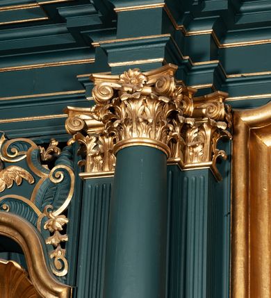 Zdjęcie nr 36: Ołtarz drewniany, dwustronny, obecnie przyścienny, architektoniczny, jednokondygnacyjny ze zwieńczeniem, trójosiowy, z bramkami. Mensa kamienna, prostopadłościenna z antepedium ujętym w profilowaną i złoconą ramę, dekorowaną kimationem jońskim i kampanulami. W polu płaskorzeźbione przedstawienie kielicha z hostią ujętego dwoma otwartymi księgami z napisem na prawej „ECCE / PANIS / ANGE/LORUM”, na lewej „EVAN/GE/LIUM”; liśćmi laurowymi, arma Christi; u podstawy kielicha nałożona korona cierniowa. W dolnych narożach antepedium dekoracja z miękko zawijającej się wstęgi regencyjnej. Tabernakulum o rozbudowanych architektonicznych formach, jednokondygnacyjne, trójosiowe, każda z osi flankowana parą kolumienek i zakończona zwieńczeniem. W osi środkowej tabernakulum metalowe: w dolnej części w formie prostopadłościennej skrzynki z wizerunkiem Chrystusa, w górnej części obrotowe z przedstawieniem Baranka Bożego, zamknięte ozdobnym zwieńczeniem z parą uskrzydlonych putt i koroną w typie zamkniętym. W polach osi bocznych umieszczone za szybką relikwie świętych ujęte prostokątną, złoconą ramą. Retabulum ustawione na wysokim, dwudzielnym cokole, z bramkami o otworach drzwiowych zamkniętych łukiem kotarowym ściętym, nadproża w formie profilowanego gryzmsu. Pole ołtarza, zarówno osi głównej jak i bocznych ujęte jest kolumnami o gładkich trzonach i złoconych kapitalach kompozytowych ustawionych na tle zwieloktrotnionych pilastrów o kanelowanych trzonach. Podpory dźwigają wyłamane na ich osi, pełne belkowanie z wydatnym, silnie profilowanych gzymsem. Na nim fragmenty przyczółka w formie wolut. Pole osi środkowej ze złoconą ramą zamkniętą łukiem wklęsło-wypukłym z uskokiem. W zwieńczeniu ramy wolutowy kartusz o nieregularnym kształcie, z napisem „CONSUMMATUM / EST”. W centrum pola ołtarzowego drewniany krycyfiks. W osi prawej figura św. Kazimierza Królewicza, w osi lewej figura św. Jadwigi Śląskiej. Rzeźby ustawione w niszach, zamkniętych łukiem wklęsło-wypukłym, na rozbudowanych, wolutowych konsolach dekorowanych z przodu kartuszem utworzonym z akantowego wieńca wypełnionego kratką regencyjną; ponad nim girlanda złożona z kampanul i kwiatów. W niszach ponad figurami umieszczone dużych rozmiarów, złocone muszle palmetowe, oraz nieco niżej dwie gałązki akantu. Ponad niszami rozbudowana płaskorzeźbiona dekoracja w formie struktury utworzonej z wolut o karbowanych wypełnieniach, w jej centrum uskrzydlone główki aniołków. Zwieńczenie w formie wklęsło-wypukłej, zamknięte gzymsem w kształcie łuku nadwieszonego, po bokach flankowane dwoma wazonami z kwiatami. W polu obraz św. Michała Archanioła. Kolorystyka ciemnozielona, ze złoceniami w partiach ornamentów oraz w załamaniach profili architektonicznych. Partie cokołu dekorowane płycinami wypełnionymi ornamentem regencyjnym. Według dokumentacji konserwatorskiej na odwrociu ołtarza znajduje się malowana iluzjonistyczna dekoracja przedstawiająca barokowy ołtarz, postacie Matki Boskiej, św. Jana Ewangelisty oraz świętych franciszkańskich.

