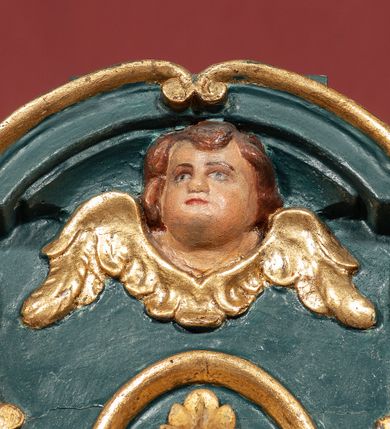 Zdjęcie nr 41: Ołtarz drewniany, dwustronny, obecnie przyścienny, architektoniczny, jednokondygnacyjny ze zwieńczeniem, trójosiowy, z bramkami. Mensa kamienna, prostopadłościenna z antepedium ujętym w profilowaną i złoconą ramę, dekorowaną kimationem jońskim i kampanulami. W polu płaskorzeźbione przedstawienie kielicha z hostią ujętego dwoma otwartymi księgami z napisem na prawej „ECCE / PANIS / ANGE/LORUM”, na lewej „EVAN/GE/LIUM”; liśćmi laurowymi, arma Christi; u podstawy kielicha nałożona korona cierniowa. W dolnych narożach antepedium dekoracja z miękko zawijającej się wstęgi regencyjnej. Tabernakulum o rozbudowanych architektonicznych formach, jednokondygnacyjne, trójosiowe, każda z osi flankowana parą kolumienek i zakończona zwieńczeniem. W osi środkowej tabernakulum metalowe: w dolnej części w formie prostopadłościennej skrzynki z wizerunkiem Chrystusa, w górnej części obrotowe z przedstawieniem Baranka Bożego, zamknięte ozdobnym zwieńczeniem z parą uskrzydlonych putt i koroną w typie zamkniętym. W polach osi bocznych umieszczone za szybką relikwie świętych ujęte prostokątną, złoconą ramą. Retabulum ustawione na wysokim, dwudzielnym cokole, z bramkami o otworach drzwiowych zamkniętych łukiem kotarowym ściętym, nadproża w formie profilowanego gryzmsu. Pole ołtarza, zarówno osi głównej jak i bocznych ujęte jest kolumnami o gładkich trzonach i złoconych kapitalach kompozytowych ustawionych na tle zwieloktrotnionych pilastrów o kanelowanych trzonach. Podpory dźwigają wyłamane na ich osi, pełne belkowanie z wydatnym, silnie profilowanych gzymsem. Na nim fragmenty przyczółka w formie wolut. Pole osi środkowej ze złoconą ramą zamkniętą łukiem wklęsło-wypukłym z uskokiem. W zwieńczeniu ramy wolutowy kartusz o nieregularnym kształcie, z napisem „CONSUMMATUM / EST”. W centrum pola ołtarzowego drewniany krycyfiks. W osi prawej figura św. Kazimierza Królewicza, w osi lewej figura św. Jadwigi Śląskiej. Rzeźby ustawione w niszach, zamkniętych łukiem wklęsło-wypukłym, na rozbudowanych, wolutowych konsolach dekorowanych z przodu kartuszem utworzonym z akantowego wieńca wypełnionego kratką regencyjną; ponad nim girlanda złożona z kampanul i kwiatów. W niszach ponad figurami umieszczone dużych rozmiarów, złocone muszle palmetowe, oraz nieco niżej dwie gałązki akantu. Ponad niszami rozbudowana płaskorzeźbiona dekoracja w formie struktury utworzonej z wolut o karbowanych wypełnieniach, w jej centrum uskrzydlone główki aniołków. Zwieńczenie w formie wklęsło-wypukłej, zamknięte gzymsem w kształcie łuku nadwieszonego, po bokach flankowane dwoma wazonami z kwiatami. W polu obraz św. Michała Archanioła. Kolorystyka ciemnozielona, ze złoceniami w partiach ornamentów oraz w załamaniach profili architektonicznych. Partie cokołu dekorowane płycinami wypełnionymi ornamentem regencyjnym. Według dokumentacji konserwatorskiej na odwrociu ołtarza znajduje się malowana iluzjonistyczna dekoracja przedstawiająca barokowy ołtarz, postacie Matki Boskiej, św. Jana Ewangelisty oraz świętych franciszkańskich.

