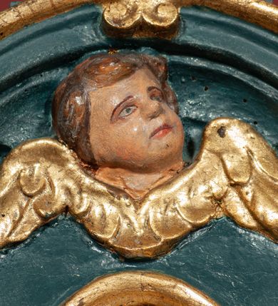 Zdjęcie nr 42: Ołtarz drewniany, dwustronny, obecnie przyścienny, architektoniczny, jednokondygnacyjny ze zwieńczeniem, trójosiowy, z bramkami. Mensa kamienna, prostopadłościenna z antepedium ujętym w profilowaną i złoconą ramę, dekorowaną kimationem jońskim i kampanulami. W polu płaskorzeźbione przedstawienie kielicha z hostią ujętego dwoma otwartymi księgami z napisem na prawej „ECCE / PANIS / ANGE/LORUM”, na lewej „EVAN/GE/LIUM”; liśćmi laurowymi, arma Christi; u podstawy kielicha nałożona korona cierniowa. W dolnych narożach antepedium dekoracja z miękko zawijającej się wstęgi regencyjnej. Tabernakulum o rozbudowanych architektonicznych formach, jednokondygnacyjne, trójosiowe, każda z osi flankowana parą kolumienek i zakończona zwieńczeniem. W osi środkowej tabernakulum metalowe: w dolnej części w formie prostopadłościennej skrzynki z wizerunkiem Chrystusa, w górnej części obrotowe z przedstawieniem Baranka Bożego, zamknięte ozdobnym zwieńczeniem z parą uskrzydlonych putt i koroną w typie zamkniętym. W polach osi bocznych umieszczone za szybką relikwie świętych ujęte prostokątną, złoconą ramą. Retabulum ustawione na wysokim, dwudzielnym cokole, z bramkami o otworach drzwiowych zamkniętych łukiem kotarowym ściętym, nadproża w formie profilowanego gryzmsu. Pole ołtarza, zarówno osi głównej jak i bocznych ujęte jest kolumnami o gładkich trzonach i złoconych kapitalach kompozytowych ustawionych na tle zwieloktrotnionych pilastrów o kanelowanych trzonach. Podpory dźwigają wyłamane na ich osi, pełne belkowanie z wydatnym, silnie profilowanych gzymsem. Na nim fragmenty przyczółka w formie wolut. Pole osi środkowej ze złoconą ramą zamkniętą łukiem wklęsło-wypukłym z uskokiem. W zwieńczeniu ramy wolutowy kartusz o nieregularnym kształcie, z napisem „CONSUMMATUM / EST”. W centrum pola ołtarzowego drewniany krycyfiks. W osi prawej figura św. Kazimierza Królewicza, w osi lewej figura św. Jadwigi Śląskiej. Rzeźby ustawione w niszach, zamkniętych łukiem wklęsło-wypukłym, na rozbudowanych, wolutowych konsolach dekorowanych z przodu kartuszem utworzonym z akantowego wieńca wypełnionego kratką regencyjną; ponad nim girlanda złożona z kampanul i kwiatów. W niszach ponad figurami umieszczone dużych rozmiarów, złocone muszle palmetowe, oraz nieco niżej dwie gałązki akantu. Ponad niszami rozbudowana płaskorzeźbiona dekoracja w formie struktury utworzonej z wolut o karbowanych wypełnieniach, w jej centrum uskrzydlone główki aniołków. Zwieńczenie w formie wklęsło-wypukłej, zamknięte gzymsem w kształcie łuku nadwieszonego, po bokach flankowane dwoma wazonami z kwiatami. W polu obraz św. Michała Archanioła. Kolorystyka ciemnozielona, ze złoceniami w partiach ornamentów oraz w załamaniach profili architektonicznych. Partie cokołu dekorowane płycinami wypełnionymi ornamentem regencyjnym. Według dokumentacji konserwatorskiej na odwrociu ołtarza znajduje się malowana iluzjonistyczna dekoracja przedstawiająca barokowy ołtarz, postacie Matki Boskiej, św. Jana Ewangelisty oraz świętych franciszkańskich.

