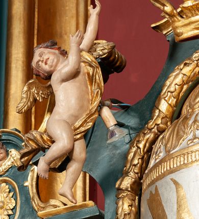 Zdjęcie nr 43: Ołtarz drewniany, dwustronny, obecnie przyścienny, architektoniczny, jednokondygnacyjny ze zwieńczeniem, trójosiowy, z bramkami. Mensa kamienna, prostopadłościenna z antepedium ujętym w profilowaną i złoconą ramę, dekorowaną kimationem jońskim i kampanulami. W polu płaskorzeźbione przedstawienie kielicha z hostią ujętego dwoma otwartymi księgami z napisem na prawej „ECCE / PANIS / ANGE/LORUM”, na lewej „EVAN/GE/LIUM”; liśćmi laurowymi, arma Christi; u podstawy kielicha nałożona korona cierniowa. W dolnych narożach antepedium dekoracja z miękko zawijającej się wstęgi regencyjnej. Tabernakulum o rozbudowanych architektonicznych formach, jednokondygnacyjne, trójosiowe, każda z osi flankowana parą kolumienek i zakończona zwieńczeniem. W osi środkowej tabernakulum metalowe: w dolnej części w formie prostopadłościennej skrzynki z wizerunkiem Chrystusa, w górnej części obrotowe z przedstawieniem Baranka Bożego, zamknięte ozdobnym zwieńczeniem z parą uskrzydlonych putt i koroną w typie zamkniętym. W polach osi bocznych umieszczone za szybką relikwie świętych ujęte prostokątną, złoconą ramą. Retabulum ustawione na wysokim, dwudzielnym cokole, z bramkami o otworach drzwiowych zamkniętych łukiem kotarowym ściętym, nadproża w formie profilowanego gryzmsu. Pole ołtarza, zarówno osi głównej jak i bocznych ujęte jest kolumnami o gładkich trzonach i złoconych kapitalach kompozytowych ustawionych na tle zwieloktrotnionych pilastrów o kanelowanych trzonach. Podpory dźwigają wyłamane na ich osi, pełne belkowanie z wydatnym, silnie profilowanych gzymsem. Na nim fragmenty przyczółka w formie wolut. Pole osi środkowej ze złoconą ramą zamkniętą łukiem wklęsło-wypukłym z uskokiem. W zwieńczeniu ramy wolutowy kartusz o nieregularnym kształcie, z napisem „CONSUMMATUM / EST”. W centrum pola ołtarzowego drewniany krycyfiks. W osi prawej figura św. Kazimierza Królewicza, w osi lewej figura św. Jadwigi Śląskiej. Rzeźby ustawione w niszach, zamkniętych łukiem wklęsło-wypukłym, na rozbudowanych, wolutowych konsolach dekorowanych z przodu kartuszem utworzonym z akantowego wieńca wypełnionego kratką regencyjną; ponad nim girlanda złożona z kampanul i kwiatów. W niszach ponad figurami umieszczone dużych rozmiarów, złocone muszle palmetowe, oraz nieco niżej dwie gałązki akantu. Ponad niszami rozbudowana płaskorzeźbiona dekoracja w formie struktury utworzonej z wolut o karbowanych wypełnieniach, w jej centrum uskrzydlone główki aniołków. Zwieńczenie w formie wklęsło-wypukłej, zamknięte gzymsem w kształcie łuku nadwieszonego, po bokach flankowane dwoma wazonami z kwiatami. W polu obraz św. Michała Archanioła. Kolorystyka ciemnozielona, ze złoceniami w partiach ornamentów oraz w załamaniach profili architektonicznych. Partie cokołu dekorowane płycinami wypełnionymi ornamentem regencyjnym. Według dokumentacji konserwatorskiej na odwrociu ołtarza znajduje się malowana iluzjonistyczna dekoracja przedstawiająca barokowy ołtarz, postacie Matki Boskiej, św. Jana Ewangelisty oraz świętych franciszkańskich.

