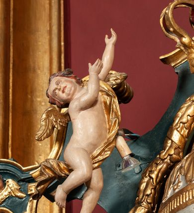 Zdjęcie nr 46: Ołtarz drewniany, dwustronny, obecnie przyścienny, architektoniczny, jednokondygnacyjny ze zwieńczeniem, trójosiowy, z bramkami. Mensa kamienna, prostopadłościenna z antepedium ujętym w profilowaną i złoconą ramę, dekorowaną kimationem jońskim i kampanulami. W polu płaskorzeźbione przedstawienie kielicha z hostią ujętego dwoma otwartymi księgami z napisem na prawej „ECCE / PANIS / ANGE/LORUM”, na lewej „EVAN/GE/LIUM”; liśćmi laurowymi, arma Christi; u podstawy kielicha nałożona korona cierniowa. W dolnych narożach antepedium dekoracja z miękko zawijającej się wstęgi regencyjnej. Tabernakulum o rozbudowanych architektonicznych formach, jednokondygnacyjne, trójosiowe, każda z osi flankowana parą kolumienek i zakończona zwieńczeniem. W osi środkowej tabernakulum metalowe: w dolnej części w formie prostopadłościennej skrzynki z wizerunkiem Chrystusa, w górnej części obrotowe z przedstawieniem Baranka Bożego, zamknięte ozdobnym zwieńczeniem z parą uskrzydlonych putt i koroną w typie zamkniętym. W polach osi bocznych umieszczone za szybką relikwie świętych ujęte prostokątną, złoconą ramą. Retabulum ustawione na wysokim, dwudzielnym cokole, z bramkami o otworach drzwiowych zamkniętych łukiem kotarowym ściętym, nadproża w formie profilowanego gryzmsu. Pole ołtarza, zarówno osi głównej jak i bocznych ujęte jest kolumnami o gładkich trzonach i złoconych kapitalach kompozytowych ustawionych na tle zwieloktrotnionych pilastrów o kanelowanych trzonach. Podpory dźwigają wyłamane na ich osi, pełne belkowanie z wydatnym, silnie profilowanych gzymsem. Na nim fragmenty przyczółka w formie wolut. Pole osi środkowej ze złoconą ramą zamkniętą łukiem wklęsło-wypukłym z uskokiem. W zwieńczeniu ramy wolutowy kartusz o nieregularnym kształcie, z napisem „CONSUMMATUM / EST”. W centrum pola ołtarzowego drewniany krycyfiks. W osi prawej figura św. Kazimierza Królewicza, w osi lewej figura św. Jadwigi Śląskiej. Rzeźby ustawione w niszach, zamkniętych łukiem wklęsło-wypukłym, na rozbudowanych, wolutowych konsolach dekorowanych z przodu kartuszem utworzonym z akantowego wieńca wypełnionego kratką regencyjną; ponad nim girlanda złożona z kampanul i kwiatów. W niszach ponad figurami umieszczone dużych rozmiarów, złocone muszle palmetowe, oraz nieco niżej dwie gałązki akantu. Ponad niszami rozbudowana płaskorzeźbiona dekoracja w formie struktury utworzonej z wolut o karbowanych wypełnieniach, w jej centrum uskrzydlone główki aniołków. Zwieńczenie w formie wklęsło-wypukłej, zamknięte gzymsem w kształcie łuku nadwieszonego, po bokach flankowane dwoma wazonami z kwiatami. W polu obraz św. Michała Archanioła. Kolorystyka ciemnozielona, ze złoceniami w partiach ornamentów oraz w załamaniach profili architektonicznych. Partie cokołu dekorowane płycinami wypełnionymi ornamentem regencyjnym. Według dokumentacji konserwatorskiej na odwrociu ołtarza znajduje się malowana iluzjonistyczna dekoracja przedstawiająca barokowy ołtarz, postacie Matki Boskiej, św. Jana Ewangelisty oraz świętych franciszkańskich.

