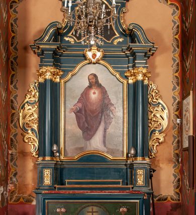 Zdjęcie nr 3: Ołtarz przyścienny, architektoniczny, jednokondygnacyjny, jednoosiowy, ze zwieńczeniem. Mensa w formie prostopadłościanu, antepedium malowane. Pośrodku medalion z wieńca laurowego. W polu wieńca krzyż oraz skrzyżowane narzędzia Męki Pańskiej na tle błękitnego nieba. Po bokach medalionu wolutowo zakręcona wić roślinna zakończona wazonami z kwiatami. Całość ukazana na ciemnozielonym tle. Retabulum umieszczone na zdwojonym cokole, flankowane kolumnami, ustawionymi na tle zwielokrotnionych pilastrów podtrzymujących wyłamane belkowanie; na osi kolumn przerwany wolutowy przyczółek. W polu głównym nastawy płytka wnęka, ujęta złoconą i profilowaną ramą w kształcie stojącego prostokąta zamkniętego łukiem wklęsło-wypukłym z uskokami. Pośrodku obraz „Najświętsze Serce Jezusa”. W górnej części ramy złocony kartusz z gorejącym sercem w polu. Zwieńczenie o delikatnie wklęsłych bokach ujętych spływami wolutowymi, zamknięte łukiem nadwieszonym. Nad nim złocona muszla palmetowa pomiędzy dwoma spływami wolutowymi. W polu zwieńczenia obraz „Św. Jan Kanty” w ramie o fantazyjnym wykroju. Retabulum flankowane po bokach ażurowymi uszami utworzonymi z liści akantu i przeplatającej je karbowanej wstęgi. Podpory ustawione na bazach, kapitele kompozytowe, trzony kolumn gładkie, natomiast trzony pilastrów kanelowane. Struktura malowana w kolorze ciemnozielonym, ornamenty i detale złocone.
