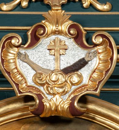 Zdjęcie nr 15: Ołtarz przyścienny, architektoniczny, jednokondygnacyjny, jednoosiowy, ze zwieńczeniem.  Mensa w formie prostopadłościanu. Antepedium malowane. Pośrodku medalion z wieńca laurowego, owiniętego sznurem. W polu wieńca godło zakonu franciszkańskiego (skrzyżowane prawe ręce Chrystusa i św. Franciszka oraz krzyż łaciński) na tle błękitnego nieba. Po bokach medalionu wolutowo zakręcona wić roślinna zakończona wazonami z kwiatami. Całość ukazana na ciemnozielonym tle. Retabulum umieszczone na zdwojonym cokole, flankowane kolumnami, ustawionymi na tle zwielokrotnionych pilastrów podtrzymujących wyłamane belkowanie; na osi kolumn przerwany wolutowy przyczółek. W polu głównym nastawy płytka wnęka, ujęta złoconą i profilowaną ramą w kształcie stojącego prostokąta zamkniętego łukiem wklęsło-wypukłym z uskokami. Pośrodku obraz „Stygmatyzacja św. Franciszka”. W górnej części ramy złocony kartusz z godłem zakonu franciszkańskiego. Zwieńczenie o delikatnie wklęsłych bokach ujętych spływami wolutowymi, zamknięte łukiem nadwieszonym. Nad nim złocona muszla palmetowa pomiędzy dwoma spływami wolutowymi. W polu zwieńczenia obraz św. Klary w ramie o fantazyjnym wykroju. Retabulum flankowane po bokach ażurowymi uszami utworzonymi z liści akantu i przeplatającej je karbowanej wstęgi. Podpory ustawione na bazach, kapitele kompozytowe, trzony kolumn gładkie, natomiast trzony pilastrów kanelowane. Struktura malowana w kolorze ciemnozielonym, ornamenty i detale złocone.
