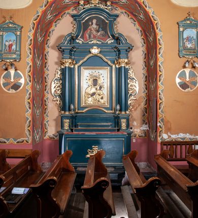 Zdjęcie nr 1: Ołtarz przyścienny, architektoniczny, jednokondygnacyjny, jednoosiowy, ze zwieńczeniem. Mensa w formie prostopadłościanu. Antepedium drewniane, w centrum złocony ormament roślinny oraz banderola.  Retabulum ustawione na zdwojonym cokole, flankowane kolumnami, ustawionych na tle zwielokrotnionych pilastrów podtrzymujących wyłamane belkowanie, na osi kolumn przerwany wolutowy przyczółek. W polu głównym nastawy płytka wnęka, ujęta złoconą i profilowaną ramą w kształcie stojącego prostokąta zamkniętego łukiem wklęsło-wypukłym z uskokami. Pośrodku obraz Matki Boskiej Częstochowskiej. W górnej części ramy złocony kartusz. Zwieńczenie o delikatnie wklęsłych bokach ze spływami wolutowymi, zamknięte łukiem nadwieszonym. Nad nim złocona muszla palmetowa ujęta dwoma spływami wolutowymi. W polu zwieńczenia obraz św. Barbary w ramie o fantazyjnym wykroju. Retabulum flankowane po bokach ażurowymi uszami utworzonymi z liści akantu. Podpory ustawione na bazach, kapitele kompozytowe, trzony kolumn gładkie, natomiast trzony pilastrów kanelowane. Struktura malowana w kolorze ciemnozielonym, ornamenty i detale złocone.