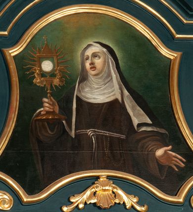 Zdjęcie nr 2: Obraz w kształcie stojącego prostokąta o wklęsło-wypukłych bokach. Przedstawia św. Klarę, ukazaną w centrum kompozycji, frontalnie, w półpostaci. Święta w prawej dłoni trzyma monstrancję, a lewą ma odsuniętą w bok; głowa jest delikatnie zwrócona w prawo i uniesiona do góry. Twarz owalna, z dużymi i migdałowymi oczami, skierowanymi w lewe górne naroże obrazu, wydatne usta, prosty i szeroki nos. Ubrana jest w habit klaryski. Tło jednolite w odcieniach zieleni i brązu, z otokiem światła wokół głowy św. Klary.