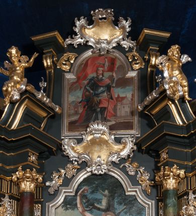 Zdjęcie nr 8: Nastawa architektoniczna, jednoosiowa z bramkami, jednokondygnacyjna ze zwieńczeniem, na dwustrefowym cokole. Ołtarz drewniany prostopadłościenny z kamienną mensą. Antepedium ujęte profilowaną ramą, wykonane z czerwonego, haftowanego aksamitu, w centrum medalion z przedstawieniem baranka leżącego na księdze, w dolnych narożach motywy kwiatowe. 
Retabulum flankowane ustawionymi pod kątem na zewnątrz dwiema parami korynckich kolumn, umieszczonych na tle kanelowanych pilastrów. Kolumny ustawione na cokołach, podtrzymują wyłamane belkowanie, przerwane nad polem środkowym, oraz przerwany falisty przyczółek. Na belkowaniu stoi para wazonów, na przerwanym przyczółku siedzą dwa putta. Pomiędzy kolumnami na cokołach znajdują się figury św. Jana Kantego i św. Jana Nepomucena. W polu głównym obraz z przedstawieniem św. Sebastiana ujęty profilowaną ramą w formie stojącego prostokąta zamkniętego łukiem półkolistym nadwieszonym z uskokiem, zwieńczoną rokokowym kartuszem flankowanym kwiatowymi zwisami. Zwieńczenie w formie stojącego prostokąta ujęte pilastrami o trzonach przechodzących w spływy wolutowe, zamknięte rokokowym kartuszem. W polu przedstawienie św. Floriana w profilowanej ramie w formie stojącego prostokąta zamkniętego łukiem półkolistym nadwieszonym. Bramki na wysokości cokołu nastawy w formie arkad podtrzymywanych przez pilastry, zwieńczonych racaille&#039;owymi szczytami. Dwustrefowy cokół dekorowany rokokowymi płycinami, rocaille&#039;m, rozetami i kartuszami. Kanelowane pilastry nastawy ozdobione kampanulami oraz bogatymi, kwiatowymi zwisami. Nastawa ujęta małymi uszami utworzonymi z liści palmy. 
Struktura architektoniczna polichromowana w kolorze czarnym, trzony kolumn pokryte polichromią imitującą kolorową marmoryzację, dekoracja rzeźbiarska, ornamentalna oraz profile pozłacane i posrebrzane. 

