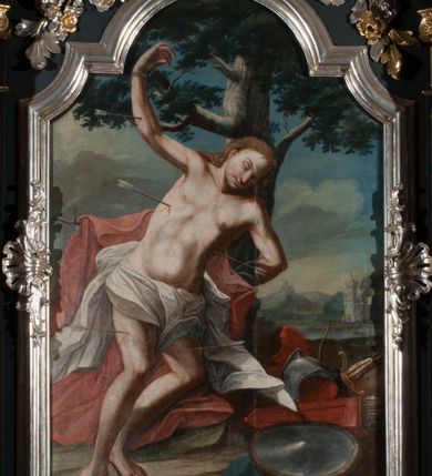 Zdjęcie nr 12: Nastawa architektoniczna, jednoosiowa z bramkami, jednokondygnacyjna ze zwieńczeniem, na dwustrefowym cokole. Ołtarz drewniany prostopadłościenny z kamienną mensą. Antepedium ujęte profilowaną ramą, wykonane z czerwonego, haftowanego aksamitu, w centrum medalion z przedstawieniem baranka leżącego na księdze, w dolnych narożach motywy kwiatowe. 
Retabulum flankowane ustawionymi pod kątem na zewnątrz dwiema parami korynckich kolumn, umieszczonych na tle kanelowanych pilastrów. Kolumny ustawione na cokołach, podtrzymują wyłamane belkowanie, przerwane nad polem środkowym, oraz przerwany falisty przyczółek. Na belkowaniu stoi para wazonów, na przerwanym przyczółku siedzą dwa putta. Pomiędzy kolumnami na cokołach znajdują się figury św. Jana Kantego i św. Jana Nepomucena. W polu głównym obraz z przedstawieniem św. Sebastiana ujęty profilowaną ramą w formie stojącego prostokąta zamkniętego łukiem półkolistym nadwieszonym z uskokiem, zwieńczoną rokokowym kartuszem flankowanym kwiatowymi zwisami. Zwieńczenie w formie stojącego prostokąta ujęte pilastrami o trzonach przechodzących w spływy wolutowe, zamknięte rokokowym kartuszem. W polu przedstawienie św. Floriana w profilowanej ramie w formie stojącego prostokąta zamkniętego łukiem półkolistym nadwieszonym. Bramki na wysokości cokołu nastawy w formie arkad podtrzymywanych przez pilastry, zwieńczonych racaille'owymi szczytami. Dwustrefowy cokół dekorowany rokokowymi płycinami, rocaille'm, rozetami i kartuszami. Kanelowane pilastry nastawy ozdobione kampanulami oraz bogatymi, kwiatowymi zwisami. Nastawa ujęta małymi uszami utworzonymi z liści palmy. 
Struktura architektoniczna polichromowana w kolorze czarnym, trzony kolumn pokryte polichromią imitującą kolorową marmoryzację, dekoracja rzeźbiarska, ornamentalna oraz profile pozłacane i posrebrzane. 

