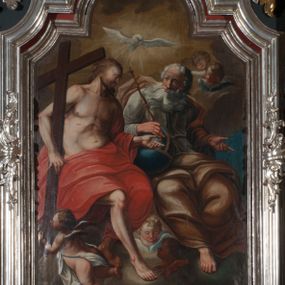 Zdjęcie nr 1: Obraz w formie stojącego prostokąta zamkniętego łukiem półkolistym nadwieszonym z uskokiem. W centrum kompozycji znajduje się grupa Trójcy Świętej. Na obłoku po lewej stronie obrazu siedzi Chrystus, po prawej Bóg Ojciec, ponad nimi unosi się gołębica Ducha Świętego. Chrystus zwrócony jest w trzech czwartych w lewo, prawą ręką przytrzymuje na ramieniu krzyż, który u dołu podtrzymuje putto, lewą rękę wyciąga w bok w geście rozmowy, prawą nogę wystawia naprzód. Twarz ma szczupłą, o dużych, migdałowatych oczach, dużym nosie i pełnych ustach, okoloną krótką, falowaną brodą oraz kręconymi włosami opadającymi na plecy. Ubrany jest w czerwony płaszcz odsłaniający tors, zarzucony na lewe ramię i opadający na nogi, na jego ciele zaznaczone są ślady męki. Bóg Ojciec zwrócony jest w trzech czwartych w lewo, z głową skierowaną w przeciwną stronę. Prawą ręką trzyma przy boku glob, w dłoni zaś berło, lewą rękę wyciąga w bok w geście rozmowy, nogi ma skrzyżowane. Jego twarz jest kwadratowa o starczych rysach, migdałowatych oczach, dużym nosie i wąskich ustach, okolona długą, białą, rozdwajającą się brodą oraz krótkimi, siwymi włosami. Ubrany jest w białą tunikę przewiązaną w pasie oraz w żółto-brązowy płaszcz zarzucony na lewe ramię, rozwiany z tyłu, opadający na nogi. Ponad głowami obu postaci unosi się gołębica Ducha Świętego w glorii promienistej. W górnym prawym rogu obrazu i u dołu dwie pary uskrzydlonych główek anielskich. Górną połowę obrazu tworzy tło wypełnione żółto-brązowymi obłokami, dolną połowę zaś błękitne niebo. 
