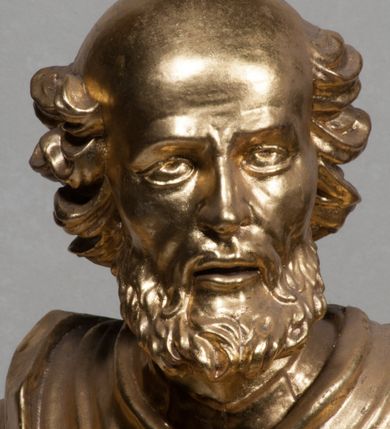 Zdjęcie nr 15: Rzeźba jest ścięta i wydrążona z tyłu, ustawiona na nieregularnej podstawie. Figura zwrócona jest frontalnie, w kontrapoście, z lekko pochylonymi głową i torsem, skierowanymi w lewo. Święty prawą ręką trzyma księgę opartą o jego biodro, lewą dłoń kładzie na piersi. Twarz ma wychudzoną, z podkreślonymi kośćmi policzkowymi, migdałowatymi, głęboko osadzonymi oczami, wąskim, małym nosem o ostrym profilu oraz wąskimi, otwartymi ustami, okoloną krótką, gęstą brodą, silnie wysuniętą do przodu oraz kręconymi włosami po bokach i z tyłu głowy. Święty ubrany jest w długą silnie fałdowaną tunikę oraz togę rektorską o szerokich rękawach, rozchyloną z przodu postaci z zygzakowato układającą się fałdą na jego prawej nodze. Figura w całości pozłocona. 
