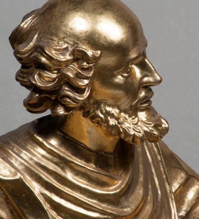 Zdjęcie nr 16: Rzeźba jest ścięta i wydrążona z tyłu, ustawiona na nieregularnej podstawie. Figura zwrócona jest frontalnie, w kontrapoście, z lekko pochylonymi głową i torsem, skierowanymi w lewo. Święty prawą ręką trzyma księgę opartą o jego biodro, lewą dłoń kładzie na piersi. Twarz ma wychudzoną, z podkreślonymi kośćmi policzkowymi, migdałowatymi, głęboko osadzonymi oczami, wąskim, małym nosem o ostrym profilu oraz wąskimi, otwartymi ustami, okoloną krótką, gęstą brodą, silnie wysuniętą do przodu oraz kręconymi włosami po bokach i z tyłu głowy. Święty ubrany jest w długą silnie fałdowaną tunikę oraz togę rektorską o szerokich rękawach, rozchyloną z przodu postaci z zygzakowato układającą się fałdą na jego prawej nodze. Figura w całości pozłocona. 
