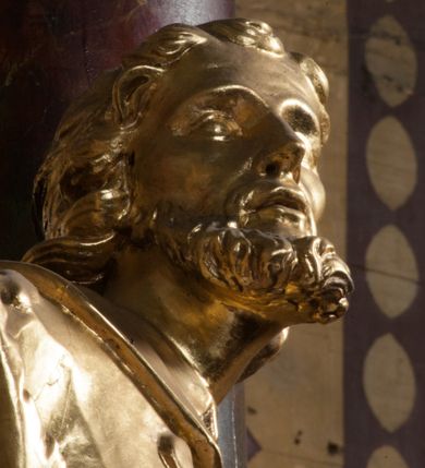 Zdjęcie nr 4: Rzeźba jest ścięta z tyłu i drążona, ustawiona na nieregularnej podstawie. Figura zwrócona jest frontalnie, w kontrapoście, z odchylonym w tył torsem i uniesioną głową, skierowaną w prawo. W prawej uniesionej wysoko ręce trzyma krucyfiks, lewą opuszczoną, wyciąga w bok. Twarz świętego jest szczupła, z uwypuklonymi kośćmi policzkowymi, migdałowatymi, głęboko osadzonymi oczami, wąskim, małym nosie o ostrym profilu oraz rozchylonymi, wąskimi ustami; okolona jest krótką, gęstą brodą wysuniętą do przodu oraz kręconymi, krótkimi włosami. Jan Nepomucen jest ubrany w długą sutannę, komżę dekorowaną przy dolnej krawędzi płaskorzeźbionym rocaille&#039;m oraz w zawiązaną na piersi almucję. Figura jest w całości pozłocona. 






