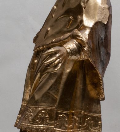 Zdjęcie nr 8: Rzeźba jest ścięta z tyłu i drążona, ustawiona na nieregularnej podstawie. Figura zwrócona jest frontalnie, w kontrapoście, z odchylonym w tył torsem i uniesioną głową, skierowaną w prawo. W prawej uniesionej wysoko ręce trzyma krucyfiks, lewą opuszczoną, wyciąga w bok. Twarz świętego jest szczupła, z uwypuklonymi kośćmi policzkowymi, migdałowatymi, głęboko osadzonymi oczami, wąskim, małym nosie o ostrym profilu oraz rozchylonymi, wąskimi ustami; okolona jest krótką, gęstą brodą wysuniętą do przodu oraz kręconymi, krótkimi włosami. Jan Nepomucen jest ubrany w długą sutannę, komżę dekorowaną przy dolnej krawędzi płaskorzeźbionym rocaille&#039;m oraz w zawiązaną na piersi almucję. Figura jest w całości pozłocona. 






