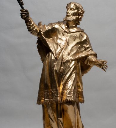 Zdjęcie nr 12: Rzeźba jest ścięta z tyłu i drążona, ustawiona na nieregularnej podstawie. Figura zwrócona jest frontalnie, w kontrapoście, z odchylonym w tył torsem i uniesioną głową, skierowaną w prawo. W prawej uniesionej wysoko ręce trzyma krucyfiks, lewą opuszczoną, wyciąga w bok. Twarz świętego jest szczupła, z uwypuklonymi kośćmi policzkowymi, migdałowatymi, głęboko osadzonymi oczami, wąskim, małym nosie o ostrym profilu oraz rozchylonymi, wąskimi ustami; okolona jest krótką, gęstą brodą wysuniętą do przodu oraz kręconymi, krótkimi włosami. Jan Nepomucen jest ubrany w długą sutannę, komżę dekorowaną przy dolnej krawędzi płaskorzeźbionym rocaille&#039;m oraz w zawiązaną na piersi almucję. Figura jest w całości pozłocona. 






