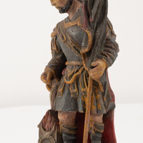 Zdjęcie nr 1: Figurka pełnoplastyczna, ustawiona na niewysokim, profilowanym cokole na planie prostokąta. Święty przedstawiony w całej postaci, zwrócony jest frontalnie, w wykroku, lekko pochylony w prawą stronę. Lewą ręką przytrzymuje przy boku chorągiew, prawą trzyma cebrzyk, z którego wylewa wodę na palący się budynek. Twarz ma szczupłą, okoloną krótką brodą. Ubrany jest w strój żołnierza: tunikę sięgającą kolan, zbroję torsową, na plecy ma zarzucony płaszcz, na głowie ma hełm z pióropuszem. Przy jego prawej nodze znajduje się niewielki budynek w płomieniach. Polichromia ciała naturalistyczna, broda brązowa, elementy stroju i chorągiew szaro-niebieskie z żółtymi detalami, płaszcz i pióropusz czerwone. 


