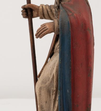 Zdjęcie nr 7: Figura jest pełnoplastyczna, ustawiona na profilowanym cokole na planie prostokąta. Święty przedstawiony w całej postaci, zwrócony jest frontalnie, w kontrapoście, z głową skierowaną w prawo. Obie ręce wyciąga przed siebie, w prawej trzyma pastorał. Twarz ma pociągłą, o  oczach skierowanych w dół, dużym, garbatym nosie i niewielkich ustach, okoloną długą brodą uformowaną w pojedyncze pukle, opadającą na pierś oraz krótkimi, silnie kręconymi włosami. Święty ubrany jest w strój biskupa: białą albę przepasaną w talii, czerwoną stułę, czerwoną kapę z niebieską podszewką, zapiętą na piersi, na głowie ma czerwoną infułę. Polichromia ciała naturalistyczna. 
