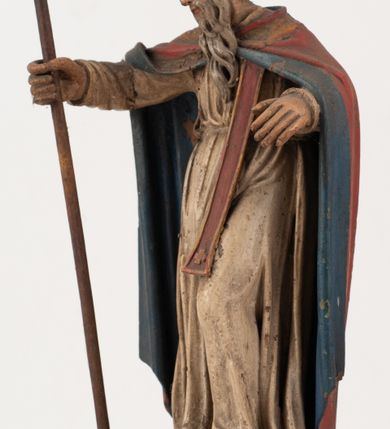 Zdjęcie nr 5: Figura jest pełnoplastyczna, ustawiona na profilowanym cokole na planie prostokąta. Święty przedstawiony w całej postaci, zwrócony jest frontalnie, w kontrapoście, z głową skierowaną w prawo. Obie ręce wyciąga przed siebie, w prawej trzyma pastorał. Twarz ma pociągłą, o  oczach skierowanych w dół, dużym, garbatym nosie i niewielkich ustach, okoloną długą brodą uformowaną w pojedyncze pukle, opadającą na pierś oraz krótkimi, silnie kręconymi włosami. Święty ubrany jest w strój biskupa: białą albę przepasaną w talii, czerwoną stułę, czerwoną kapę z niebieską podszewką, zapiętą na piersi, na głowie ma czerwoną infułę. Polichromia ciała naturalistyczna. 
