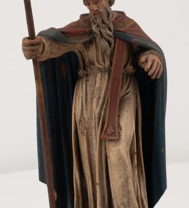 Zdjęcie nr 3: Figura jest pełnoplastyczna, ustawiona na profilowanym cokole na planie prostokąta. Święty przedstawiony w całej postaci, zwrócony jest frontalnie, w kontrapoście, z głową skierowaną w prawo. Obie ręce wyciąga przed siebie, w prawej trzyma pastorał. Twarz ma pociągłą, o  oczach skierowanych w dół, dużym, garbatym nosie i niewielkich ustach, okoloną długą brodą uformowaną w pojedyncze pukle, opadającą na pierś oraz krótkimi, silnie kręconymi włosami. Święty ubrany jest w strój biskupa: białą albę przepasaną w talii, czerwoną stułę, czerwoną kapę z niebieską podszewką, zapiętą na piersi, na głowie ma czerwoną infułę. Polichromia ciała naturalistyczna. 
