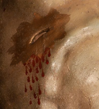 Zdjęcie nr 9: Figura umarłego Chrystusa przybita jest trzema gwoździami do prostego krzyża. Ciało w lekkim zwisie, o szeroko rozłożonych ramionach, układających się w delikatny łuk, głowa opada bezwładnie na prawe ramię, nogi są delikatnie ugięte w kolanach, stopy skrzyżowane w układzie prawa na lewą. Twarz pociągła, o łagodnych rysach i niskim czole, zamkniętych oczach, dużym nosie i rozchylonych ustach, okolona krótką, rozdwajającą się brodą oraz silnie kręconymi włosami opadającymi na prawy bark. Na głowie korona cierniowa. Ciało wychudzone, smukłe, o miękko modelowanej muskulaturze oraz silnie zaznaczonych żebrach i mostku klatki piersiowej, z podkreślonymi liniami ścięgien w partiach ramion i nóg. Biodra przepasane ekspresyjnie drapowanym perizonium zawieszonym na podwójnym sznurze, sięgającym połowy ud, odsłaniającym prawe biodro, ze zwisem rozwianej tkaniny na prawym boku. Polichromia naturalistyczna w partiach ciała z zaznaczonymi śladami męki, perizonium i korona cierniowa pozłacane. W górnej części krzyża banderola z inskrypcją „I.N. / R.I.”.



