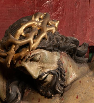 Zdjęcie nr 11: Figura umarłego Chrystusa przybita jest trzema gwoździami do prostego krzyża. Ciało w lekkim zwisie, o szeroko rozłożonych ramionach, układających się w delikatny łuk, głowa opada bezwładnie na prawe ramię, nogi są delikatnie ugięte w kolanach, stopy skrzyżowane w układzie prawa na lewą. Twarz pociągła, o łagodnych rysach i niskim czole, zamkniętych oczach, dużym nosie i rozchylonych ustach, okolona krótką, rozdwajającą się brodą oraz silnie kręconymi włosami opadającymi na prawy bark. Na głowie korona cierniowa. Ciało wychudzone, smukłe, o miękko modelowanej muskulaturze oraz silnie zaznaczonych żebrach i mostku klatki piersiowej, z podkreślonymi liniami ścięgien w partiach ramion i nóg. Biodra przepasane ekspresyjnie drapowanym perizonium zawieszonym na podwójnym sznurze, sięgającym połowy ud, odsłaniającym prawe biodro, ze zwisem rozwianej tkaniny na prawym boku. Polichromia naturalistyczna w partiach ciała z zaznaczonymi śladami męki, perizonium i korona cierniowa pozłacane. W górnej części krzyża banderola z inskrypcją „I.N. / R.I.”.



