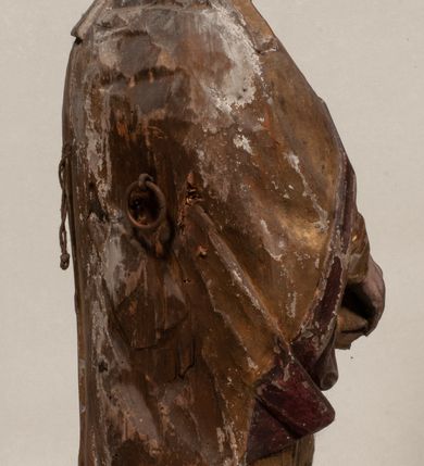 Zdjęcie nr 5: Figura nieopracowana z tyłu, ustawiona na niewielkiej podstawie. Święty ukazany jest w całej postaci, frontalnie, w kontrapoście, z pochyloną głową skierowaną w lewo. W prawej, opuszczonej wzdłuż ciała ręce trzyma zamkniętą księgę, w lewej, uniesionej przed sobą na wysokości piersi – wiosło. Jego twarz jest trójkątna o migdałowatych oczach, krótkim nosie i wąskich ustach, okolona brodą. Ubrany jest w albę, rokietę oraz płaszcz z kołnierzem zapięty pod szyją, na głowie ma infułę. Polichromia naturalistyczna w partiach ciała, strój i atrybuty złocone. 
