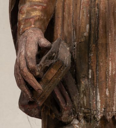 Zdjęcie nr 11: Figura nieopracowana z tyłu, ustawiona na niewielkiej podstawie. Święty ukazany jest w całej postaci, frontalnie, w kontrapoście, z pochyloną głową skierowaną w lewo. W prawej, opuszczonej wzdłuż ciała ręce trzyma zamkniętą księgę, w lewej, uniesionej przed sobą na wysokości piersi – wiosło. Jego twarz jest trójkątna o migdałowatych oczach, krótkim nosie i wąskich ustach, okolona brodą. Ubrany jest w albę, rokietę oraz płaszcz z kołnierzem zapięty pod szyją, na głowie ma infułę. Polichromia naturalistyczna w partiach ciała, strój i atrybuty złocone. 
