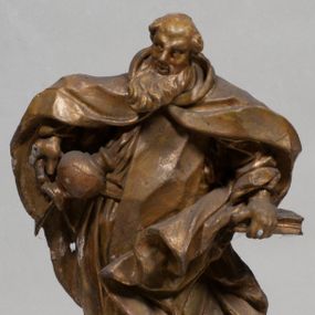 Zdjęcie nr 1: Rzeźba pełnoplastyczna, zwrócona jest frontalnie, w kontrapoście, łukowato przegięta w lewo. Święty lewą ręką trzyma przy boku zamkniętą księgą, w prawej zaś odwrócony dzban, z którego wylewa się woda. Jego twarz jest szczupła, o głęboko osadzonych oczach, dużym, krótkim nosie i pełnych rozchylonych ustach, okolona długą, gęstą brodą, silnie wysuniętą do przodu oraz kręconymi włosami po bokach głowy. Prorok jest ubrany w silnie drapowany habit przewiązany w pasie, ze szkaplerzem oraz płaszcz z kapturem zapięty pod szyją, opadający na ramiona, z zawiniętą przy lewym boku partią ekspresyjnie rozwianej tkaniny. Figura w całości pozłocona. 





